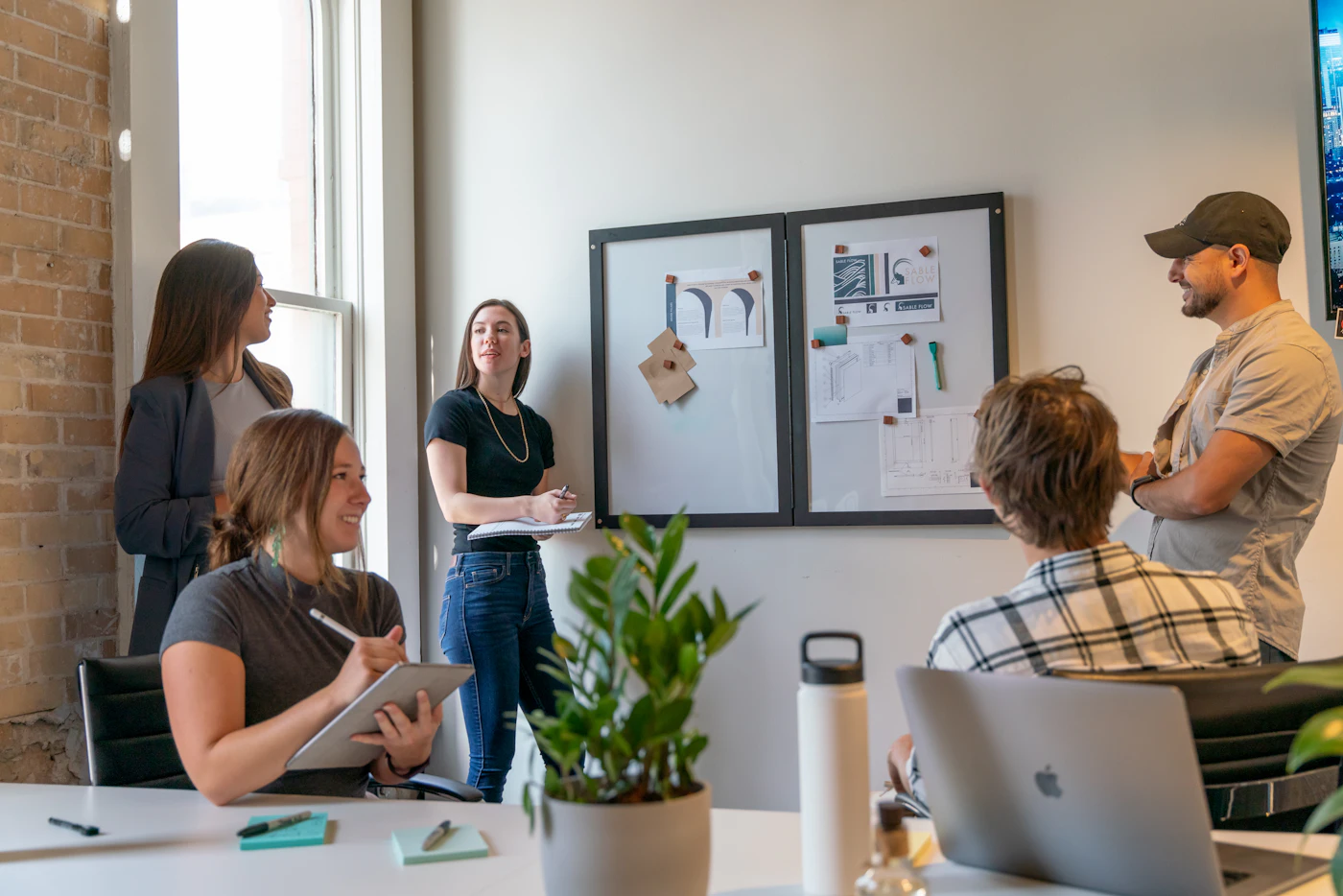A small team meeting around a whiteboard in a sunlit office