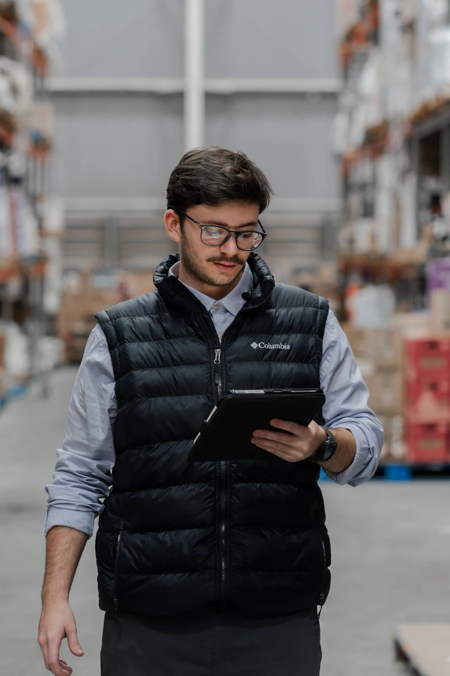 A manager checking a tablet on a warehouse floor